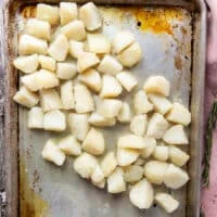 The drained potatoes added into the hot baking sheet with hot oil