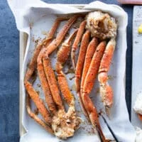 crab legs on a baking sheet seasoned with cajun spice blend and drizzled with olive oil.