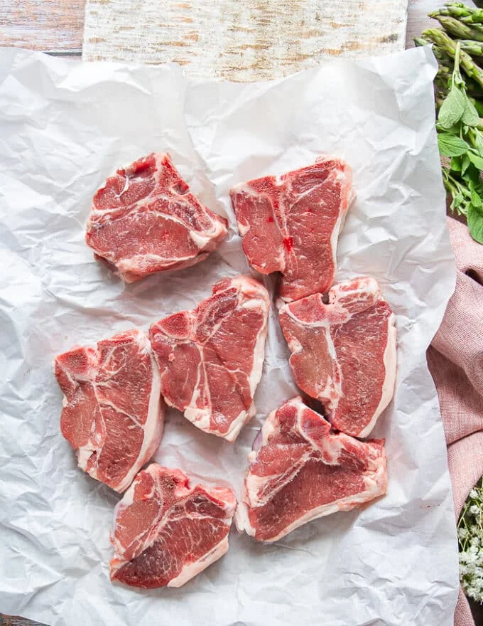 lamb chops trimmed and raw on a paper on the counter