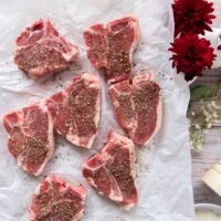 lamb chops on a paper seasoned liberally with coarse salt and pepper on both sides