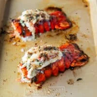 lobster tails on a baking sheet broiled and slathered in herb butter