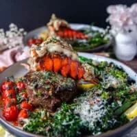 A full plate of fillet mignon cooked perfectly and a lobster tail on tops with herb butter drizzling, some rapini on the side, lemon wedges and parmesan cheese for the final surf and turf plate