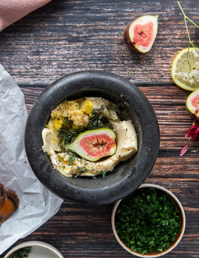 The herb butter ingredients added into a large mortar and pestle