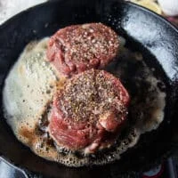 tenderloin steaks added to a cast iron skillet with butter and oil