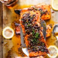 A spatula holding a piece of sweet chili salmon close up, cooked and ready