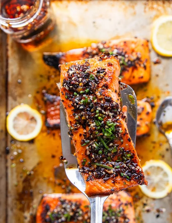 A spatula holding a piece of sweet chili salmon close up, cooked and ready