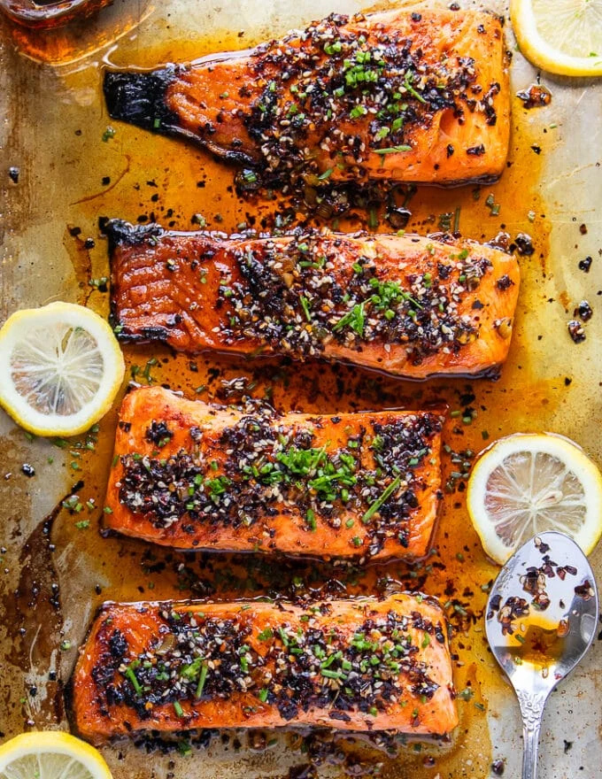finished sweet chili salmon in a baking sheet garnished with extra sesame seeds and green onions minced over the top