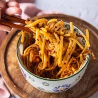 two chopsticks holding up crab pasta showing the chili pasta and the crabs