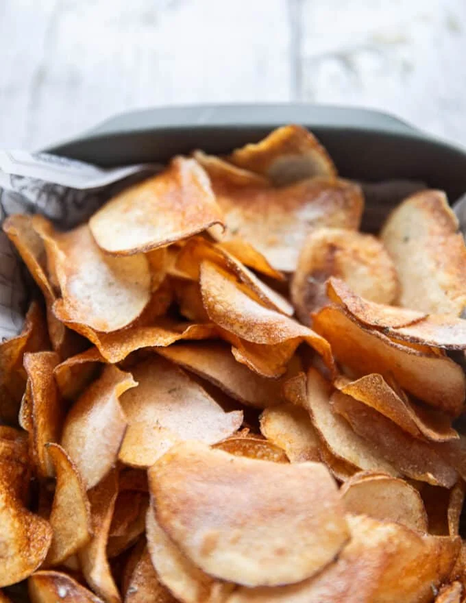 close up of crispy fried potato chips showing the crispiness and seasoning and golden color