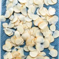 The potato slices spread in a single layer over a kitchen towel to dry