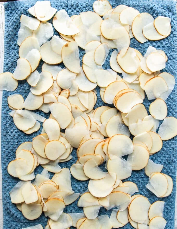 The potato slices spread in a single layer over a kitchen towel to dry