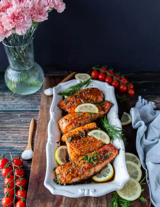 A full plate of maple salmon with all the maple glaze and lemon wedges along with lemon slices garnishing it