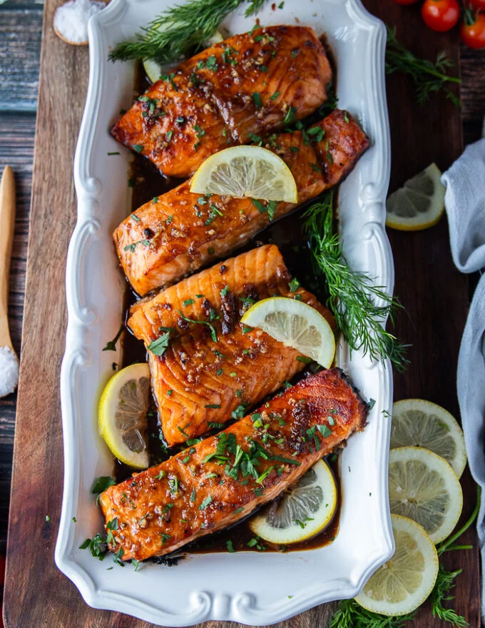 finished plate of maple glazed salmon fillets served with lemon slices