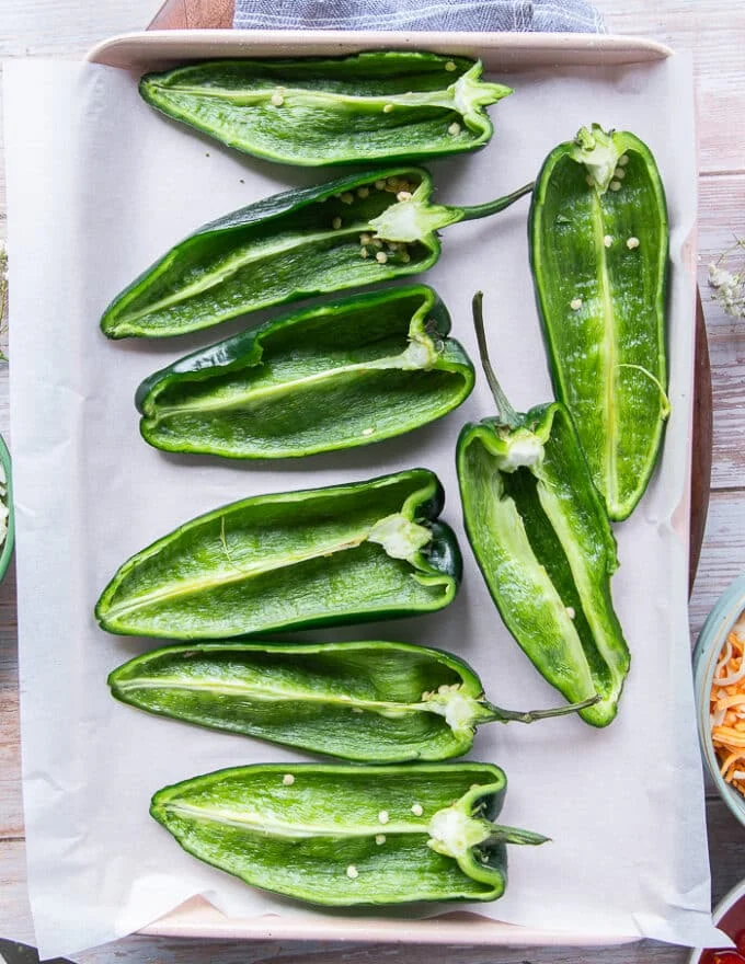 Poblano peppers cut in half and laid. on a baking sheet with cut up side facing up