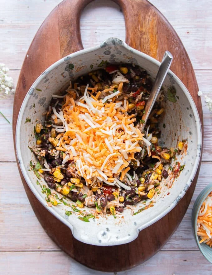 The shredded cheese is added to the bowl of the filling