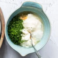 A bowl with all the dressing ingredients added in and a spoon used to mix it up