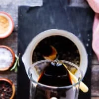 a hand pouring some balsamic vinegar in to a pot to make balsamic glaze