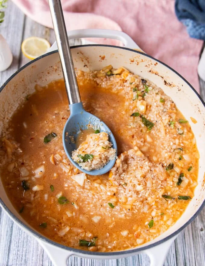 the first batch of lobster stock is added over the rice in the skillet to make risotto
