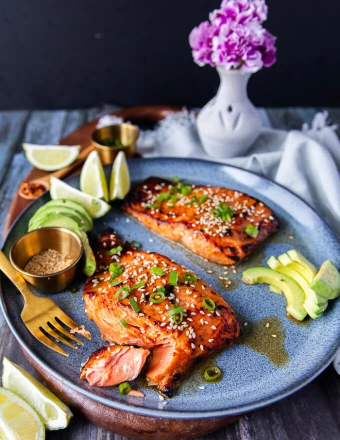 A plate with miso salmon and avocado and a fork breaking up the salmon showing how succulent it is