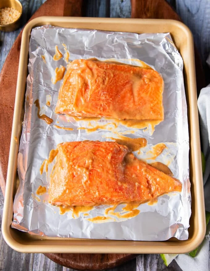 The salmon fillet drenched in miso marinade on both sides on a baking sheet