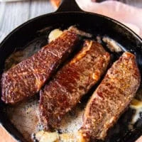 flipped steak basted with butter in a cast iron skillet with a beautiful golden crust