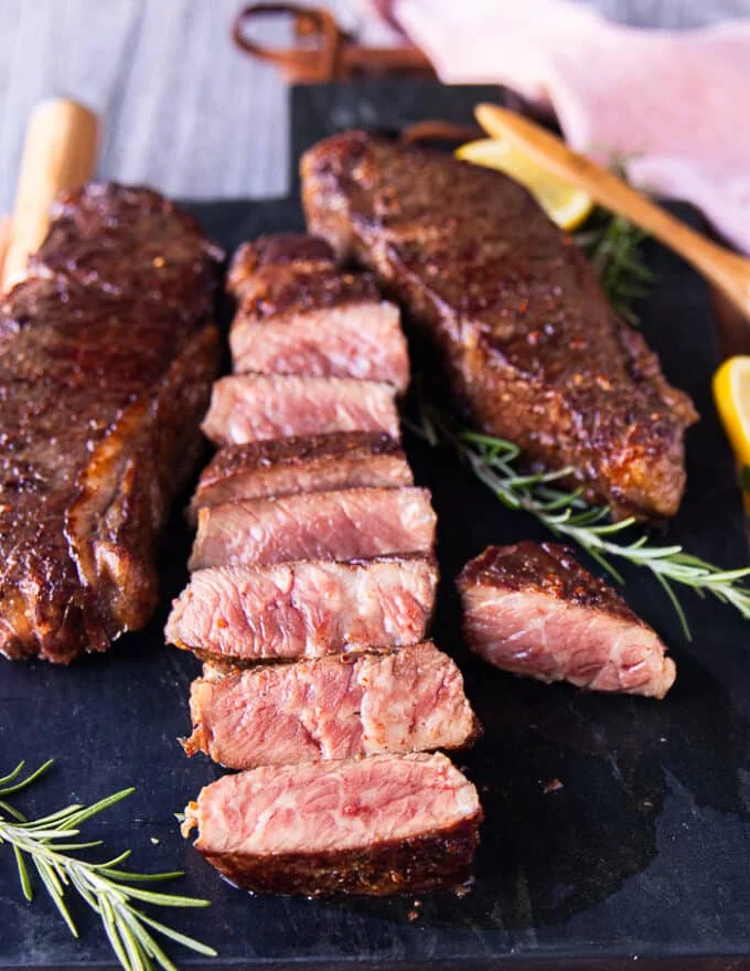 A sliced reverse sear steak on a black marble showing the perfect medium rare cooked inside of the steaks
