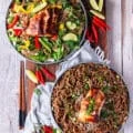two plates of soba noodles, one served warm and the other cold with veggies