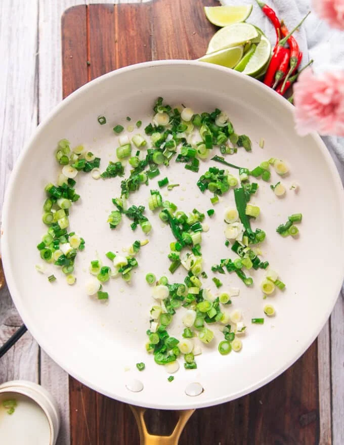 green onions cooking in a skillet with sesame oil