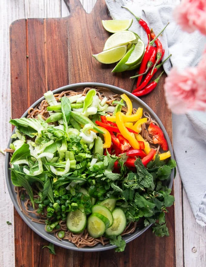 the veggies and herbs are added over the cooked and cooled soba noodles.