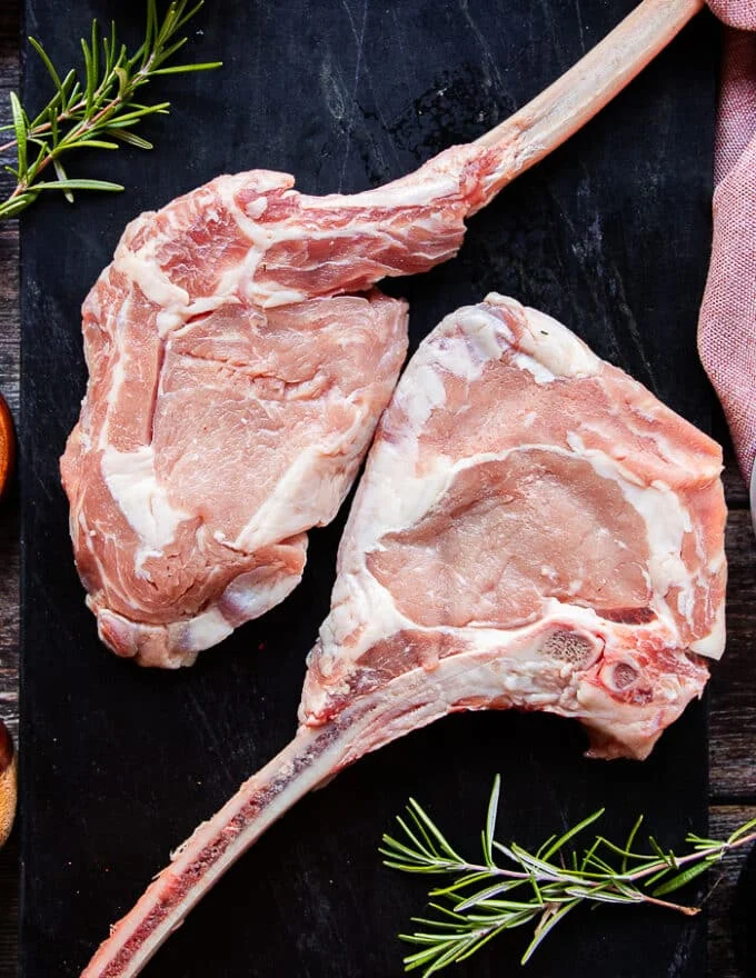 two french cut veal chops on a black marble showing the premium cut of veal chops close up