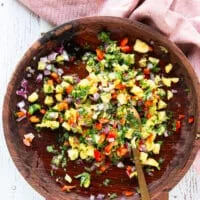 All the pineapple salsa ingredients are tossed and mixed well in a large wooden bowl and seasoned.