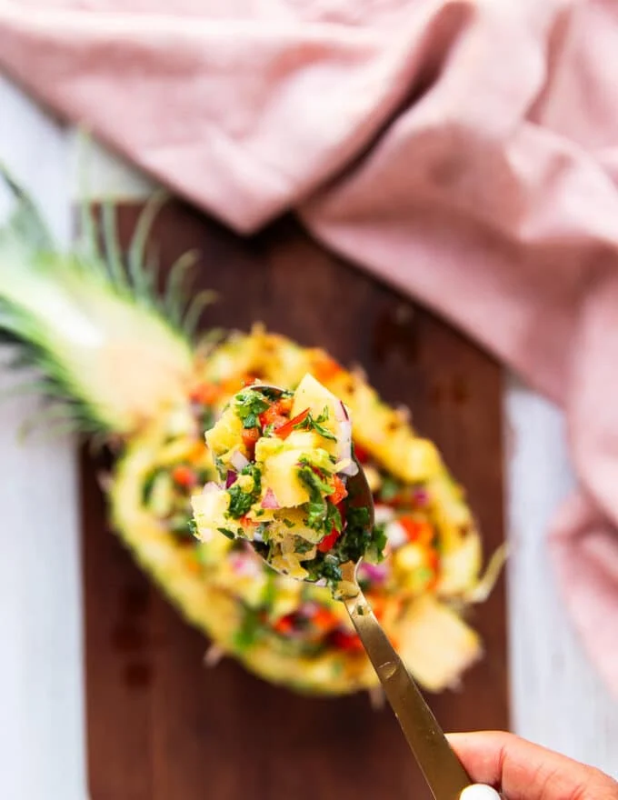 A spoon holding close a spoonful of pineapple salsa showing the texture of it