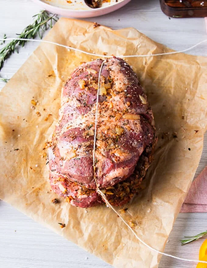 The first step to tying up the boneless leg of lamb is to tie the meat vertically and make a tight knot