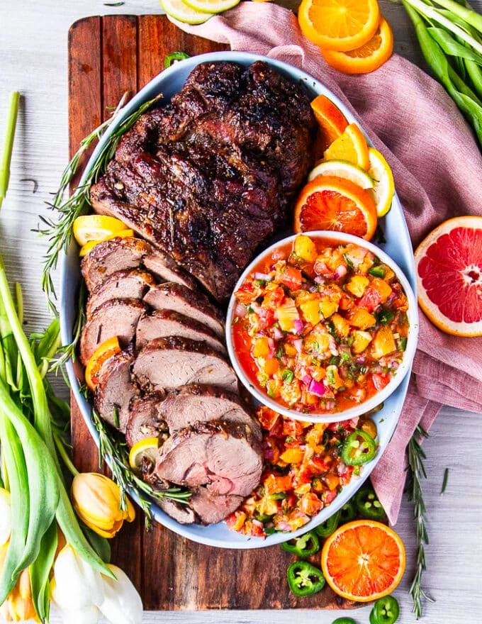 Top view of a fully roasted boneless leg of lamb, thinly sliced and arranged on a plate