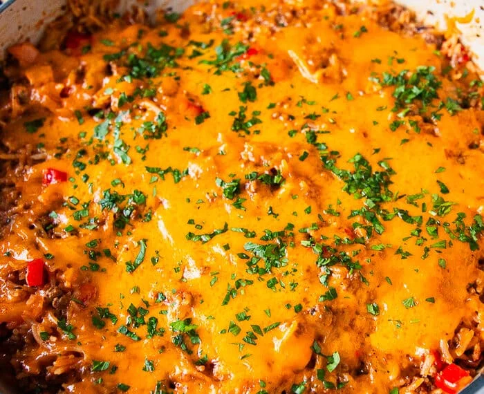 close up of a stuffed pepper casserole showing the melted cheese on top, the cooked rice, meat and peppers underneath
