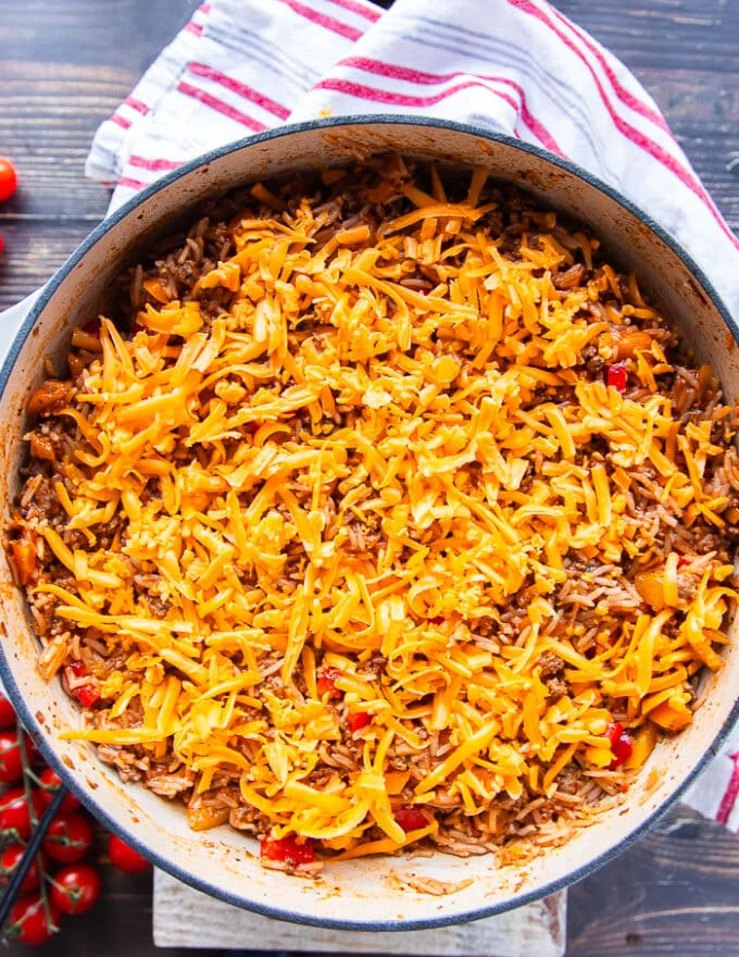 A layer of cheddar cheese is loaded over the stuffed pepper casserole and ready for the oven