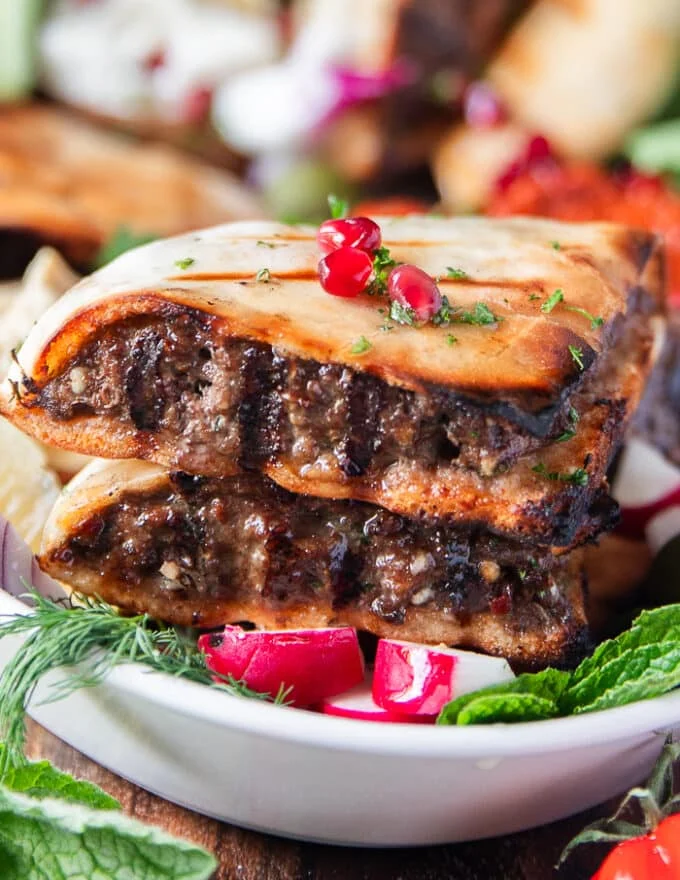 close up of one arayes meat stuffed pita showing the grill marks on the meat and bread, the juicy meat and crisp bread