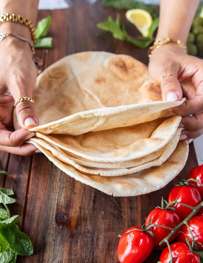 A hand holding a stack of thin pita breads to show what they look like