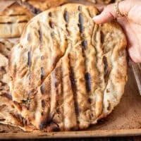 a hand holding a fully cooked arayes off the grill