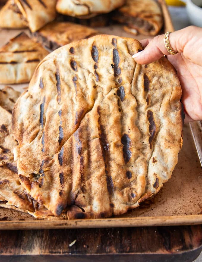 a hand holding a fully cooked arayes off the grill
