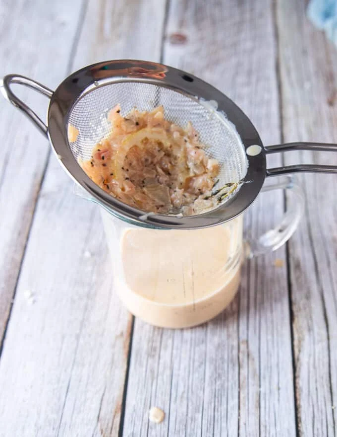 The creamy lemon sauce for black cod recipe is ready and passed through a sieve to strain in a cup