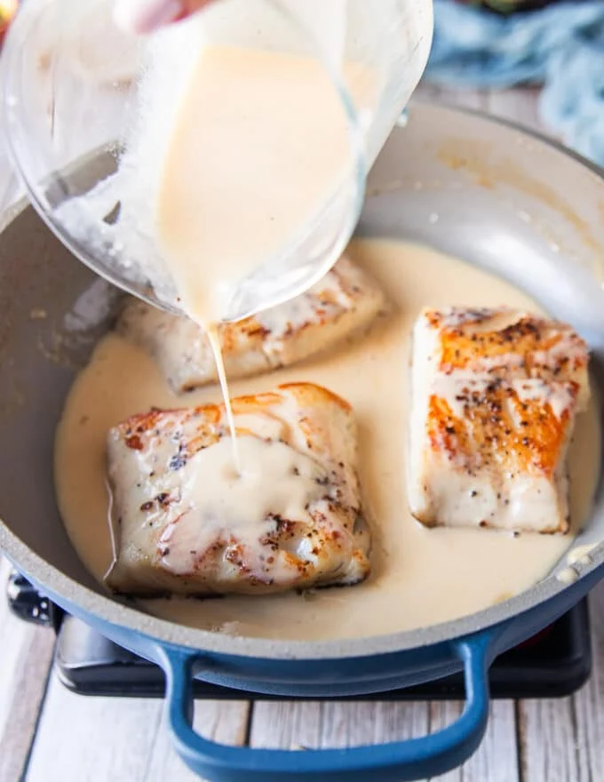the cooked black cod is returned to the skillet and the creamy lemon beurre blanc sauce is poured right over it