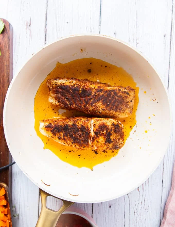 charred and seared cajun spiced halibut or chicken in a skillet