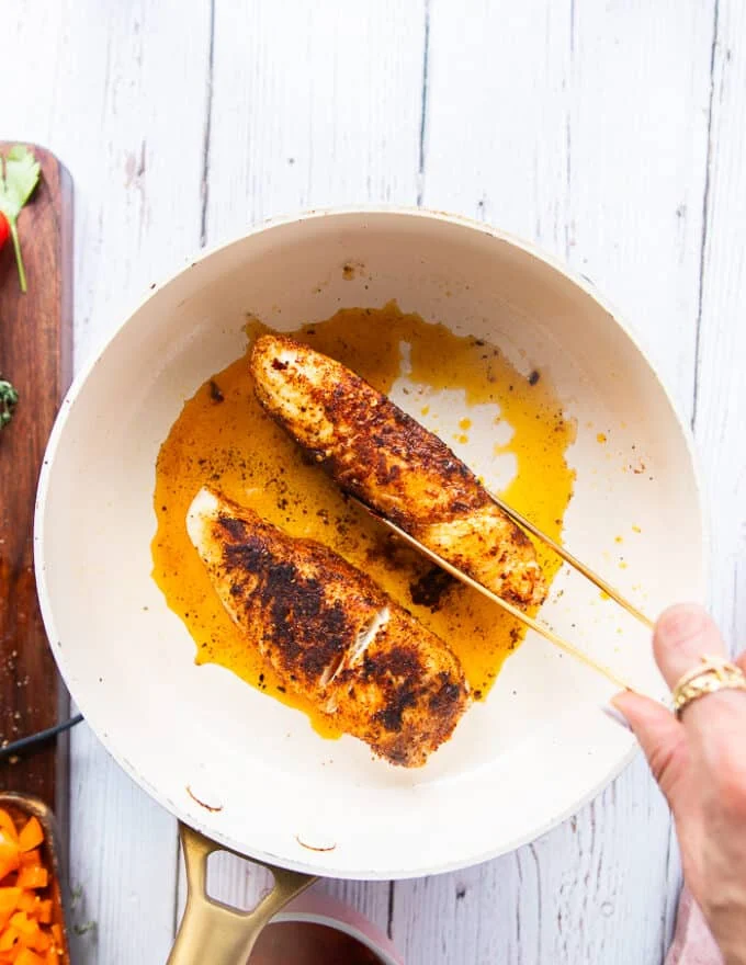 A hand holding tongs and showing how to sear the sides as well for maximum char and flavor