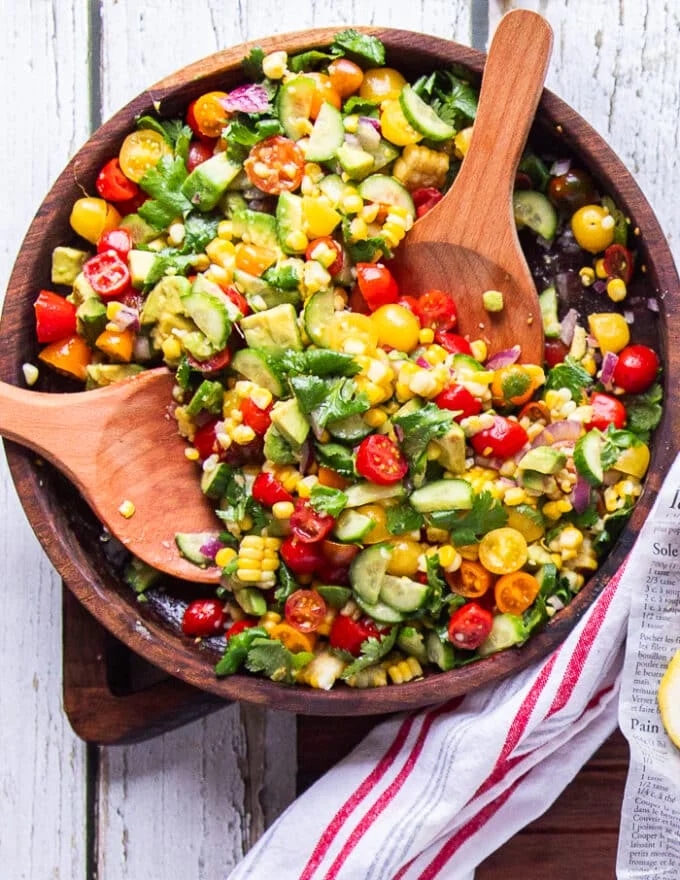 final bowl of corn and tomato salad with two wooden handles