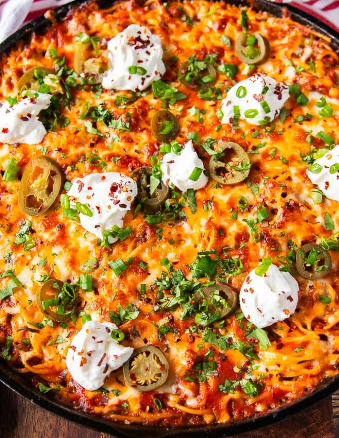 close up of a small piece of the taco spaghetti skillet showing the texture of the melted cheese, and toppings