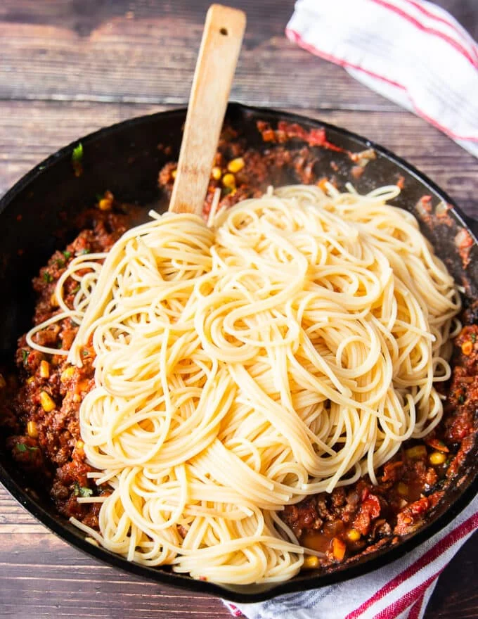 Cooked spaghetti is now added over the skillet with the taco beef and sauce