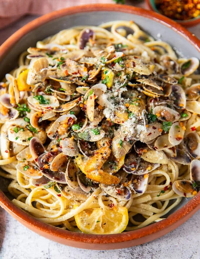 close up of the clam pasta on a plate showing the texture of the pasta, clam sauce and the cooked clams