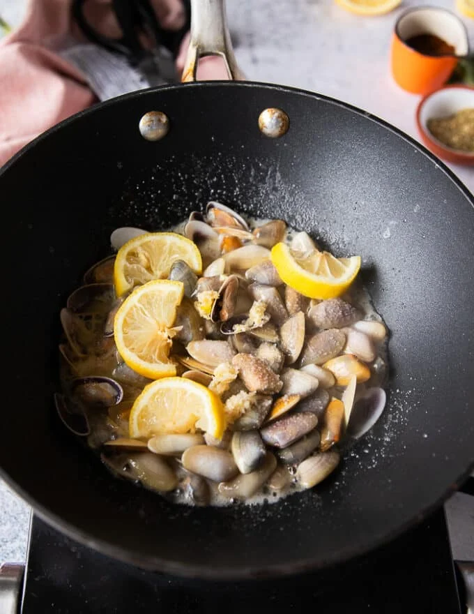 the garlic and lemon slices cooking in a skillet to make the clam pasta