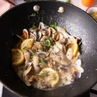 The clams are added and starting to exude some water and create a sauce in the pan